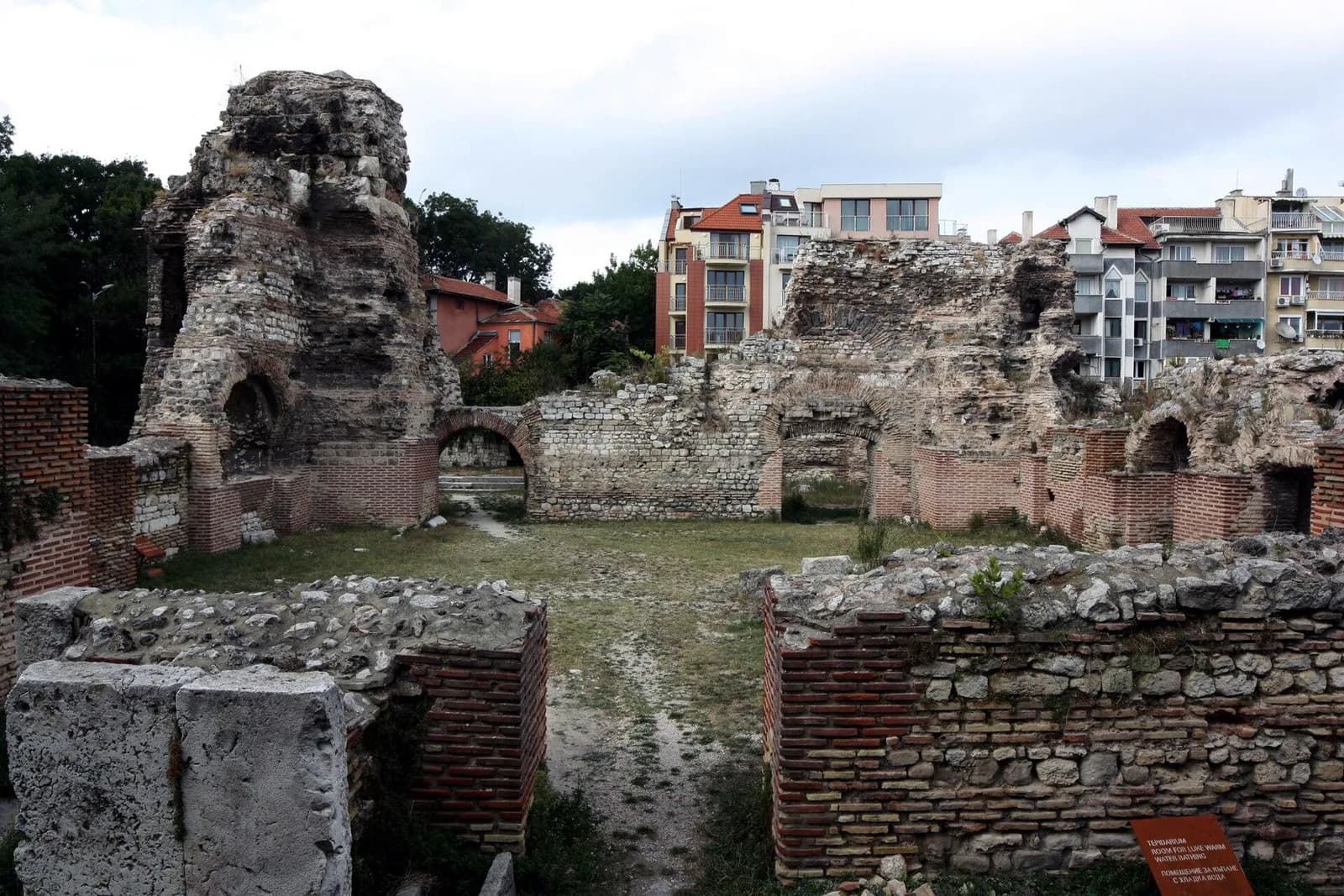 Broken Roman masonry walls among modern buildings at Varna’s ancient baths.