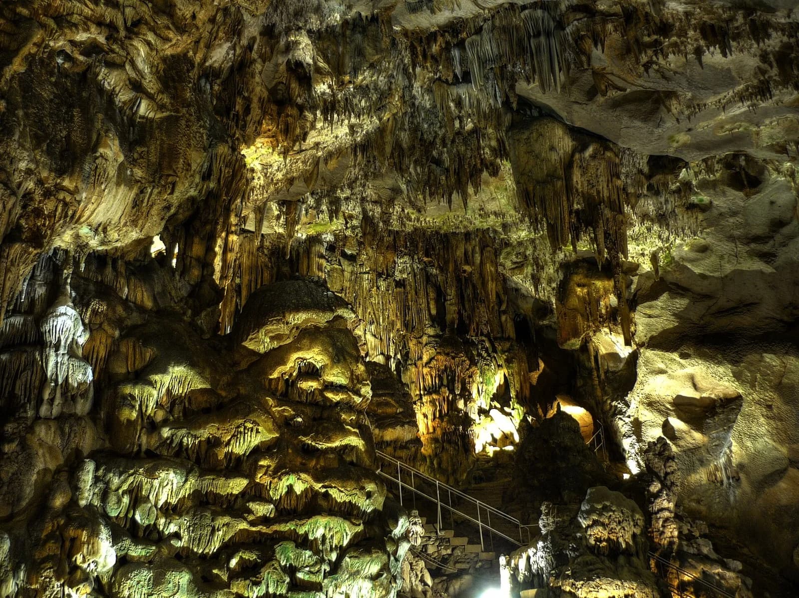 Illuminated cave formations and railing inside Ledenika Cave