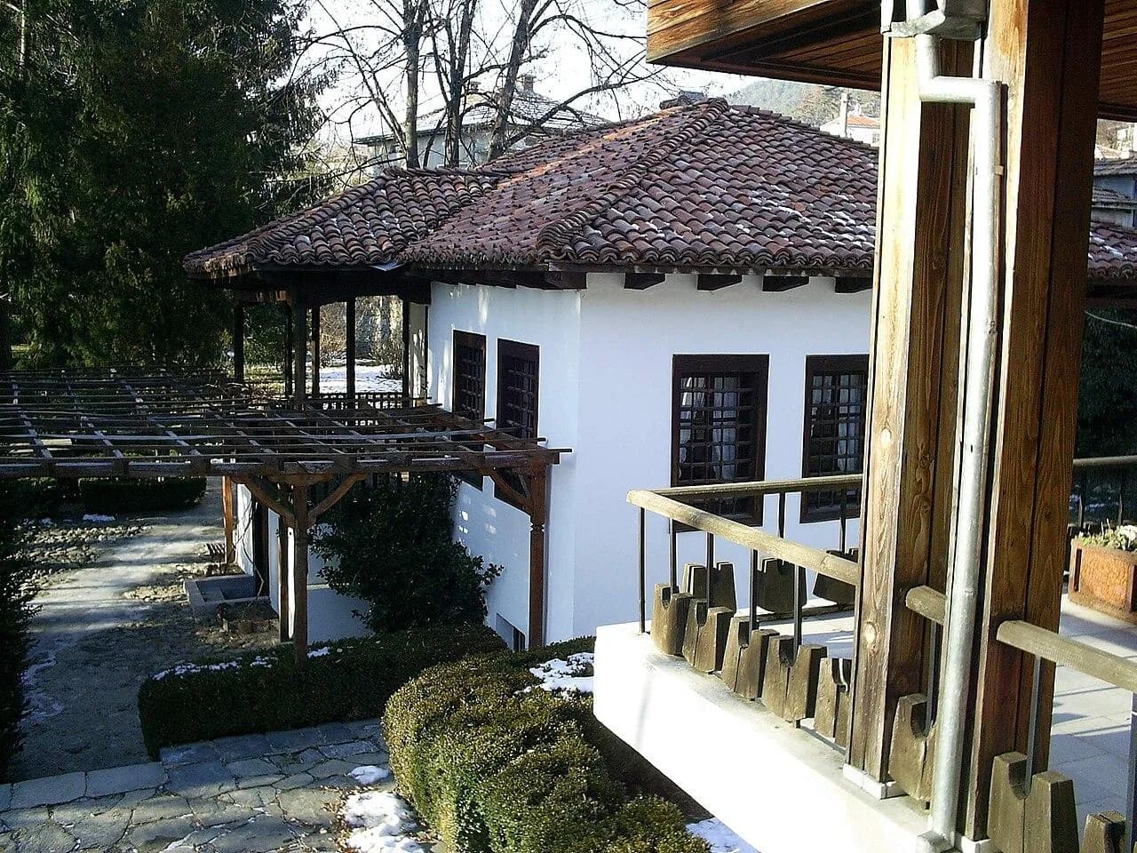 A white historic house with a tiled roof and wooden porch in the Botev museum complex.