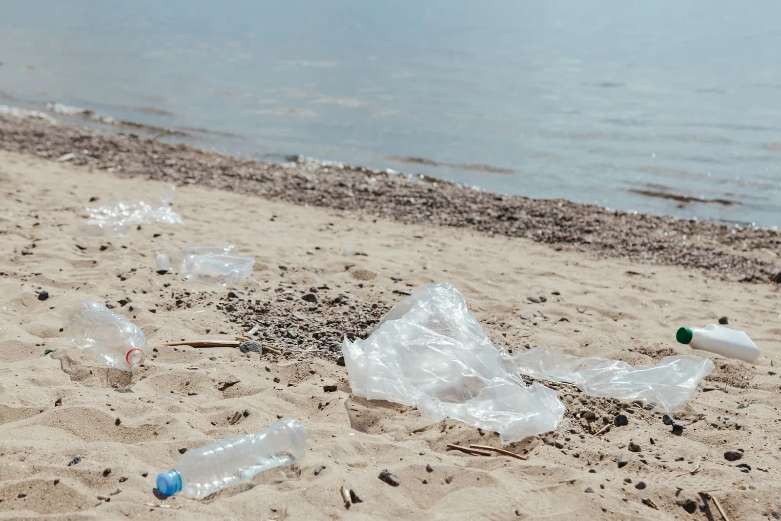 Discarded plastic bottle and other litter on a sandy beach