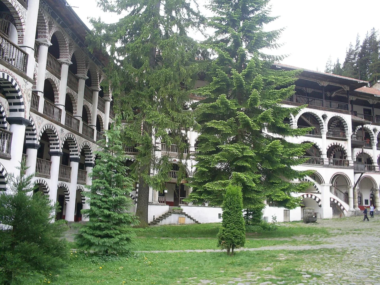 The arcaded courtyard buildings and a tall tree at Rila Monastery