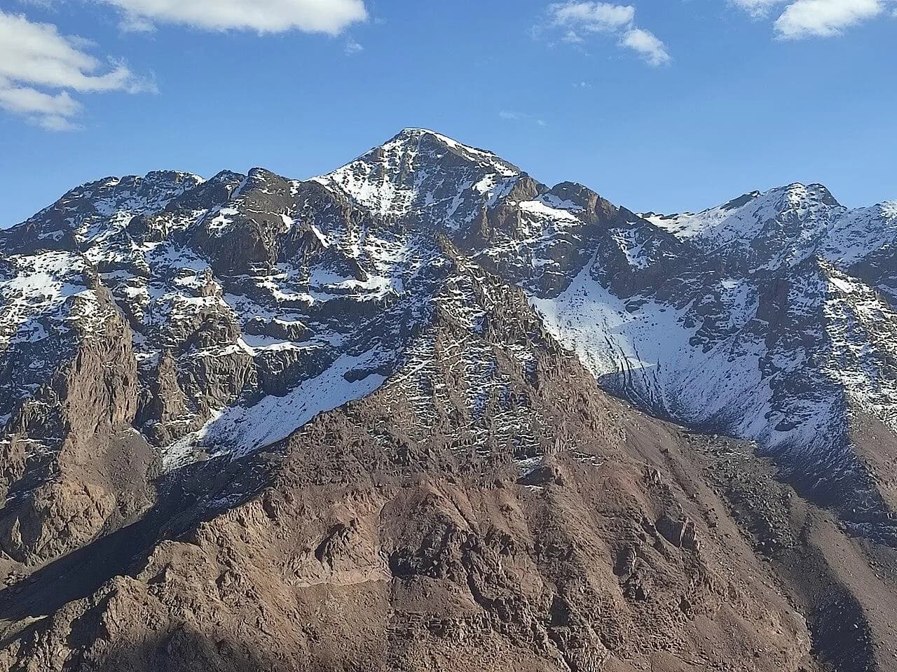 Toubkal’s steep rocky summit and snow patches against a blue sky.