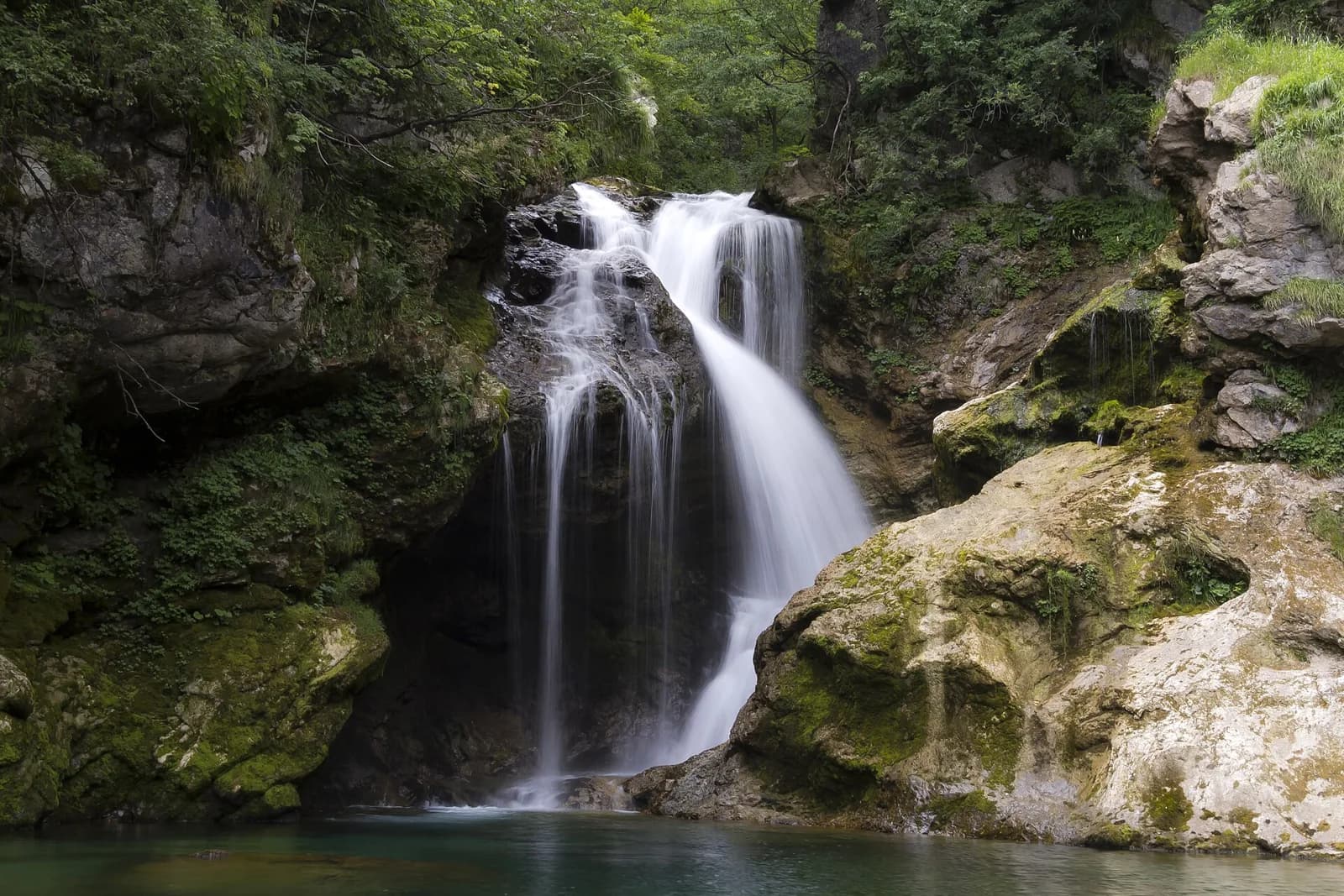 A waterfall framed by rocks and greenery in Vintgar Gorge